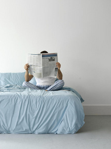 在床上看报纸的人