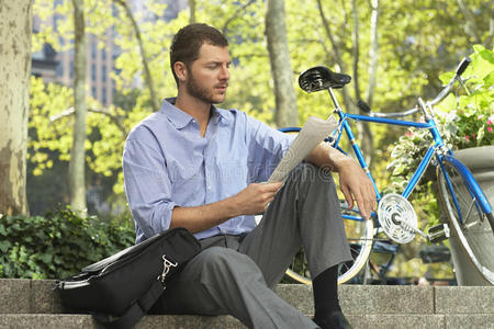骑自行车看报纸的商人