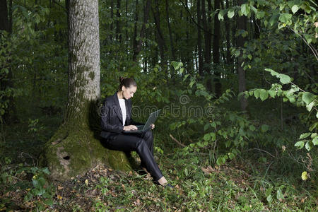 在森林里使用笔记本电脑的女商人