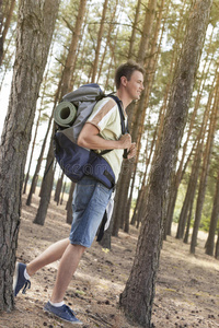 背着背包在森林中行走的男性徒步旅行者的全方位侧视图