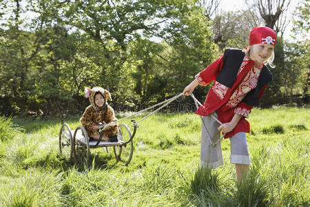 穿海盗服装的孩子拉着车上穿捷豹服装的男孩照片