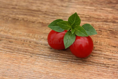 两个红色成熟的西红柿和罗勒放在木制背景上