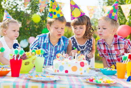 生日聚会上孩子们在蛋糕上吹蜡烛