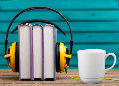 堆叠的书籍和耳机和一杯咖啡