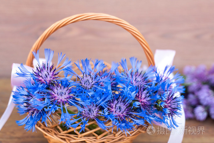 与蓝色的矢车菊在篮子里的乡村风格背景