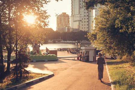 一个女人沿着路走到河岸上日落的风景城市公园
