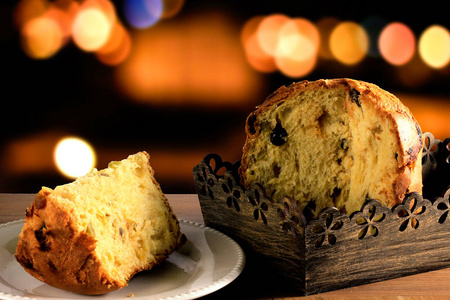 特写 panettone 内框在木桌上, 散景背景与灯光, 前视图