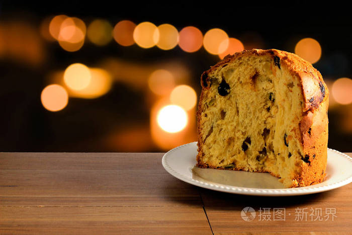 木桌上的陶瓷板材特写panettone, 散景背景带灯, 前视图照片-正版商用 