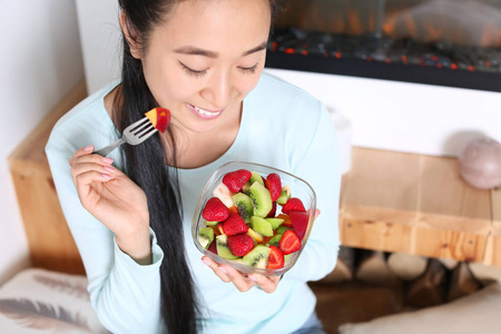 亚洲妇女在家吃健康水果沙拉