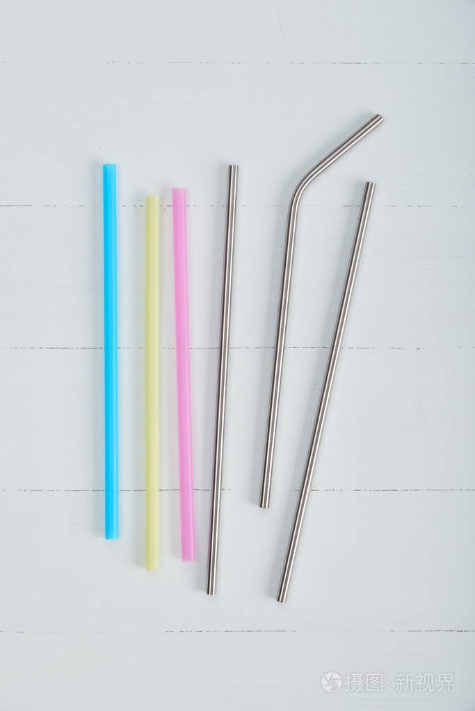 可重复使用的不锈钢吸管和一次性彩色吸管在木桌上照片-正版商用图片0
