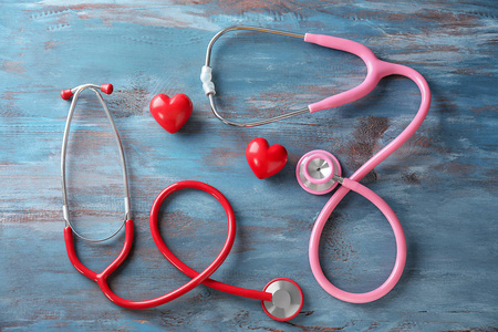 医疗听诊器和红色的心在木质背景。心脏病学概念