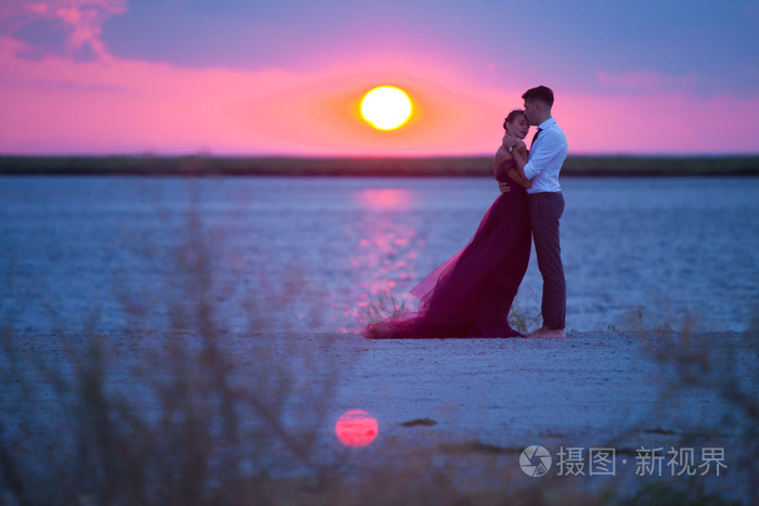 看日落海滩上放松的年轻浪漫情侣