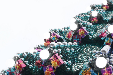 一棵巨大的圣诞树的碎片, 上面有许多装饰品礼品盒和夜光灯。一张装饰圣诞树特写照片与复制空间