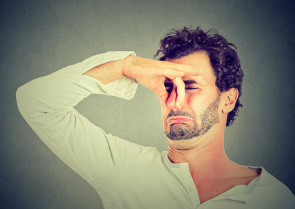 男人脸上的厌恶地捏鼻子,臭臭难闻的气味照片