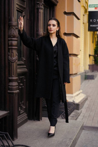 穿着黑色衣服的华丽的年轻黑发妇女在街上摆姿势