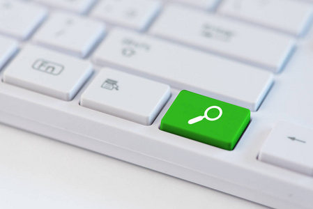 白色笔记本电脑键盘上带有放大镜符号图标符号的绿色密钥