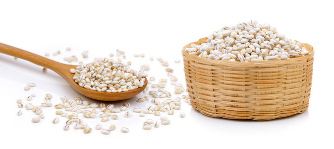 大麦籽粒在白色背景上篮和木勺子