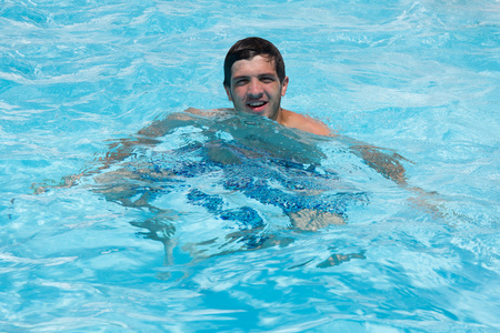 快乐有魅力的男人在碧蓝的海水，在泳池里