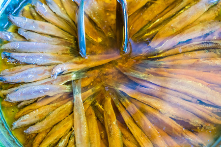 腌制的土耳其凤尾鱼鱼片在盐水与钳子在金属托盘, 关闭, 高角度视图