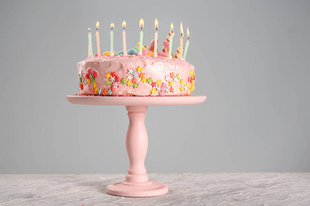 与美味的生日蛋糕和在桌上燃烧蜡烛站在一起