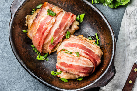 鸡肉裹在熏肉里。顶部视图。石板背景