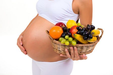 近距离的怀孕的肚子和异国情调的水果篮子。健康怀孕维生素