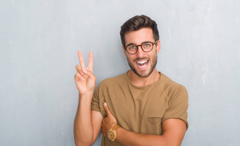 的垃圾墙上戴着眼镜微笑着, 脸上闪烁着欢快的表情, 正在做胜利的手势