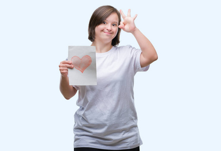 唐氏综合征青年妇女持有红心卡在孤立的背景下做 ok 标志与手指, 优秀的标志