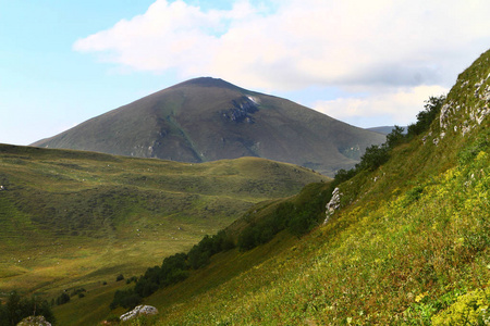 美丽的山坡自然风景相片与绿色草甸在浅蓝色天空背景照片