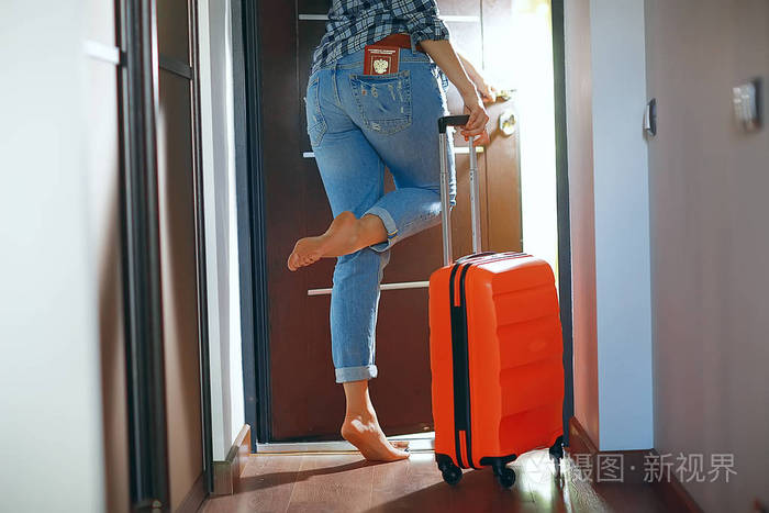 女人带着一个红色的手提箱离开房间, 旅游的概念, 出发