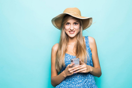 时尚微笑的女人使用智能手机戴草帽在蓝色背景