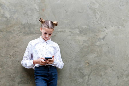 严肃的年轻女孩在白色衬衣网上上网手机, 看着屏幕上集中表达