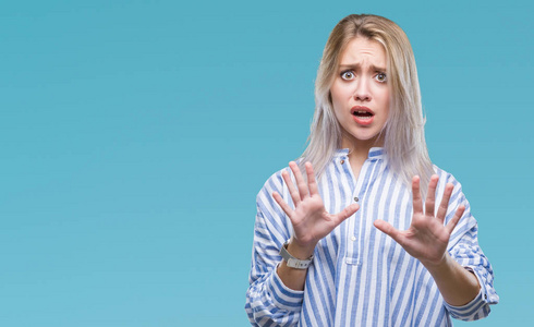 年轻的金发女人在孤立的背景下害怕和恐惧的表情用手停止手势, 在震惊