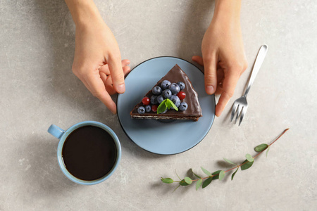 妇女与切片巧克力海绵浆果蛋糕在餐桌上, 顶部视图
