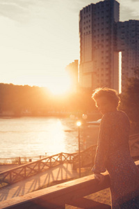 在河岸的公园里看日落的女人