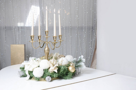新年的装饰品和一支燃烧蜡烛的金色烛台站在一架白色大钢琴的表面上。