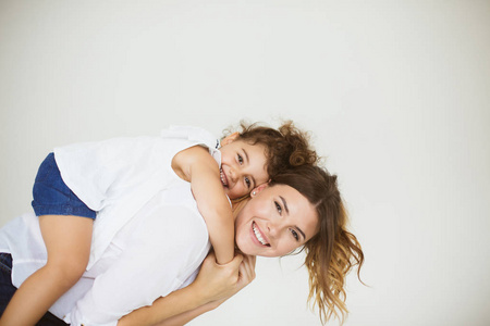 欢快的母亲抱着小微笑的女儿回来快乐地看着在一起的白色背景相机