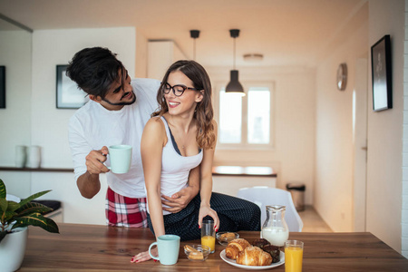 微笑的年轻夫妇，享受一起吃早餐，喝咖啡的照片