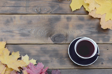 一杯茶, 在一组黄色的秋天落叶的背景表面上的深棕色天然木板