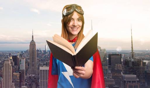 美丽的超级英雄女孩读书在摩天大楼城市