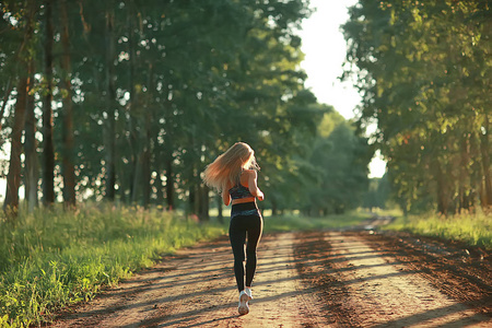 在夏日森林里奔跑的迷人女人。年轻运动妇女户外慢跑