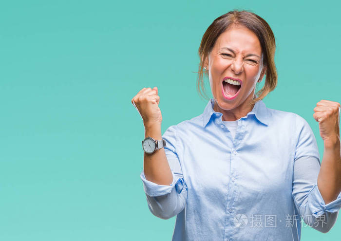 中年资深西班牙裔妇女在孤立的背景下非常高兴和兴奋做赢家手势与手臂