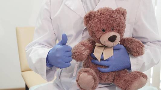 专业医生抱着泰迪熊, 竖起大拇指