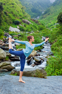 女人做瑜伽体式 Natarajasana 户外在瀑布