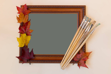 画框, 油漆刷子和五颜六色的秋天叶子在柔和的背景