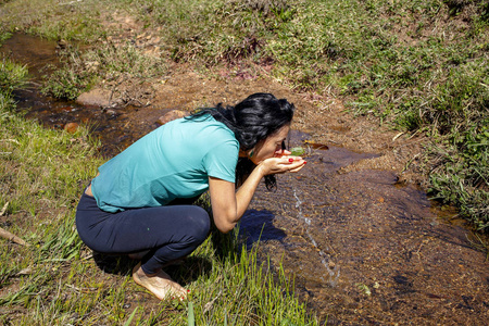 在清澈的小溪里喝水的女人