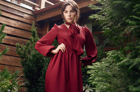 华丽的黑发妇女的肖像在时尚红色礼服摆在花园里