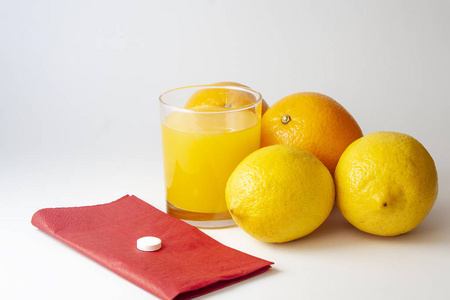 药片放在红色餐巾上, 上面放着一杯果汁柠檬和橙色的白色。医疗理念