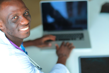 在桌子上的笔记本电脑上工作的年轻非洲医生