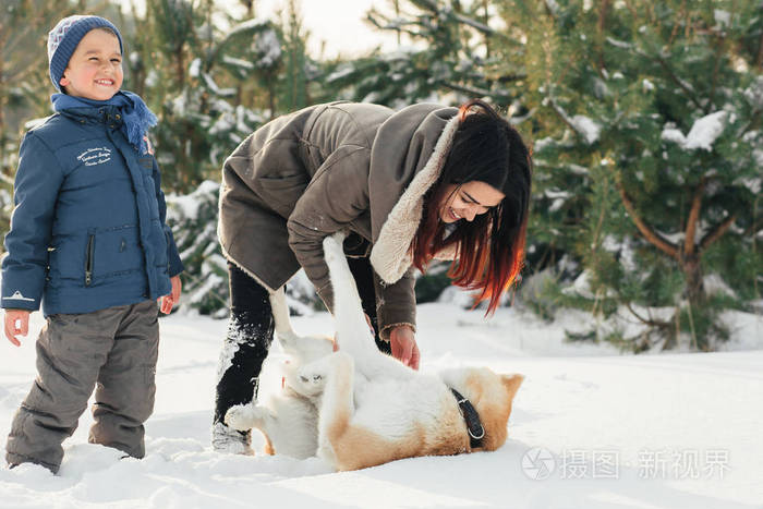 圣诞节快乐的家庭, 母亲和儿子带着狗躺在冬天的雪地上散步.